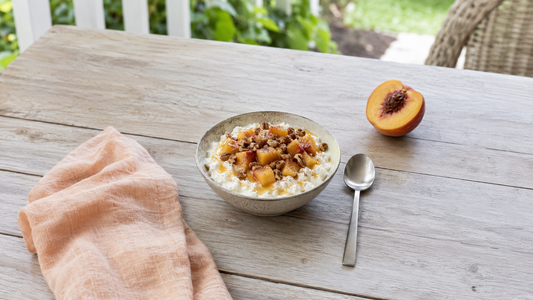 Peach cobbler cottage cheese bowl with fresh peaches, pecans, cinnamon, and Biotics³